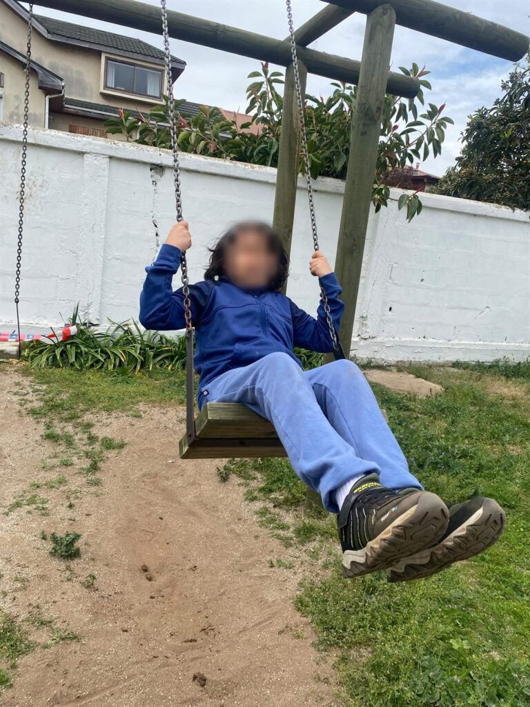 Niño columpiándose en el patio de Crecer Autista